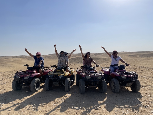 People on quad bikes in a desert landscape.