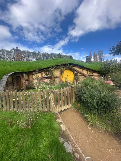       Hobbit-style house with a yellow door in a garden.
  