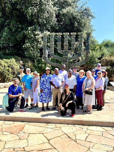 A large group of people posing in front of a large sculpture.