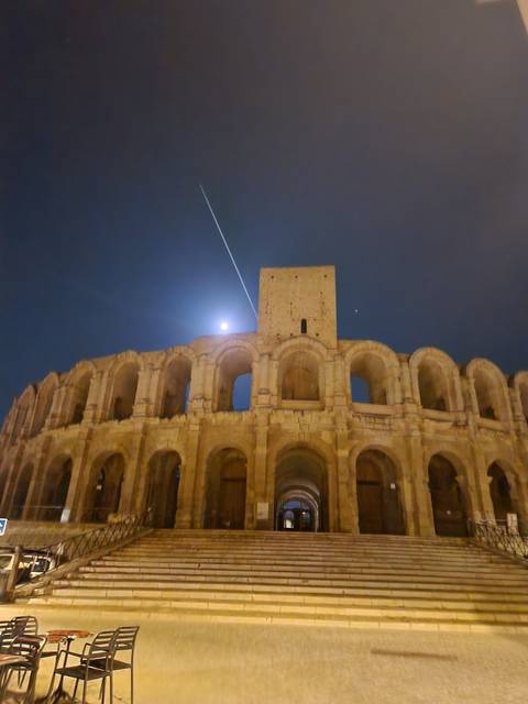 Ancient Roman amphitheater at night with a bright moon.