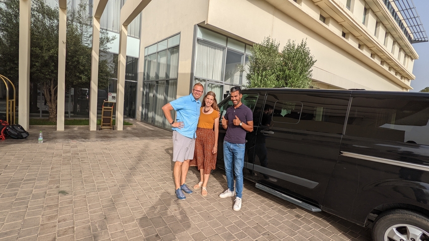 Three individuals posing in front of a van.