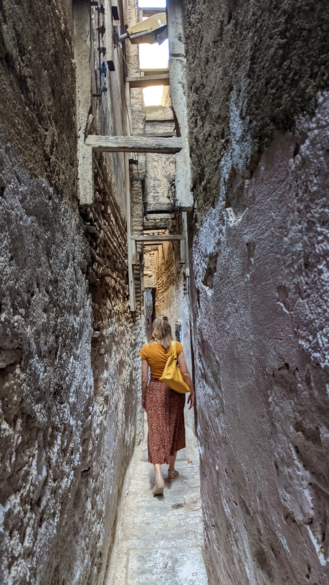 A person walking through a narrow, ancient alleyway.
