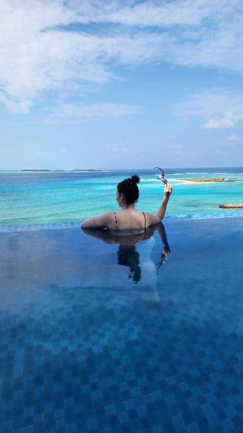 Person in an infinity pool facing the ocean.