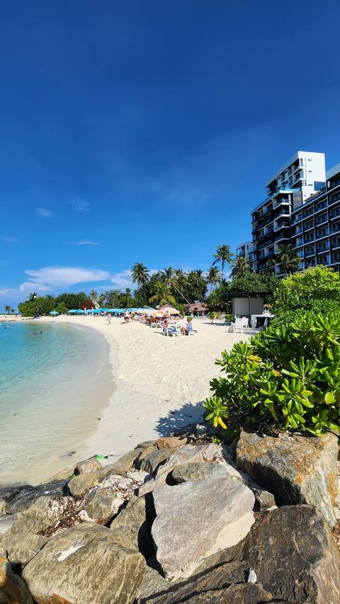 Beach with a sandy area and a hotel in the background.
