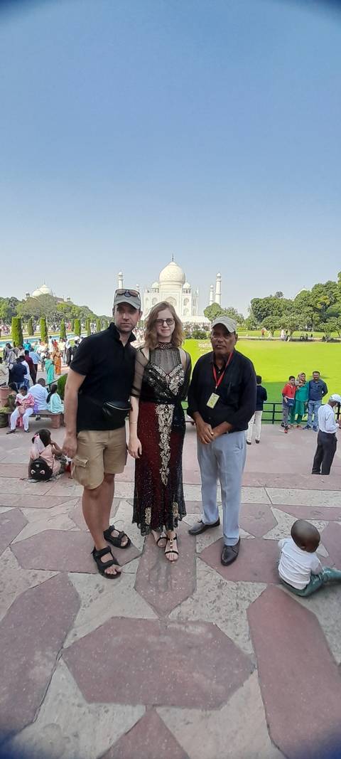       People posing in front of the Taj Mahal.
  