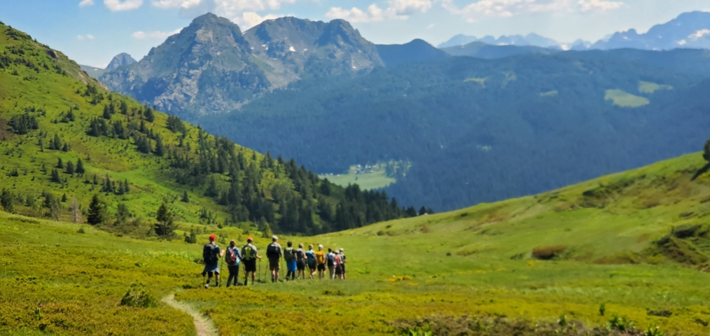 Hikers walking uphill in a green mountainous landscape.