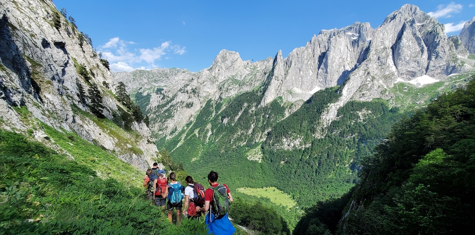 Group of hikers walking along a ridge with stunning mountain views.