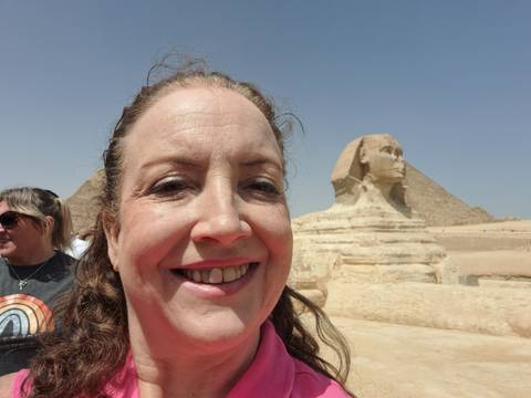 Partially visible person with a large sphinx sculpture in the background.