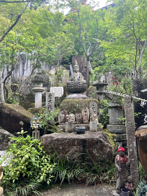 Rock garden with Buddha statues and greenery.