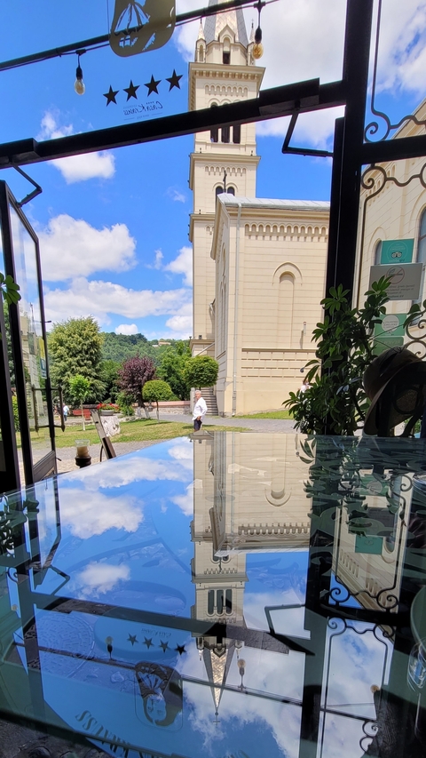 View of a building and garden through a window, with a person walking outside.