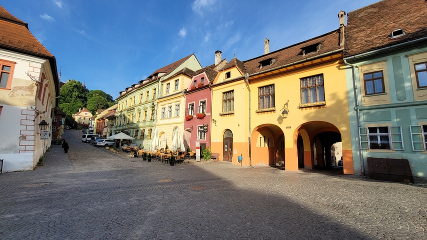 Colorful buildings along a cobblestone street with a clear blue sky.