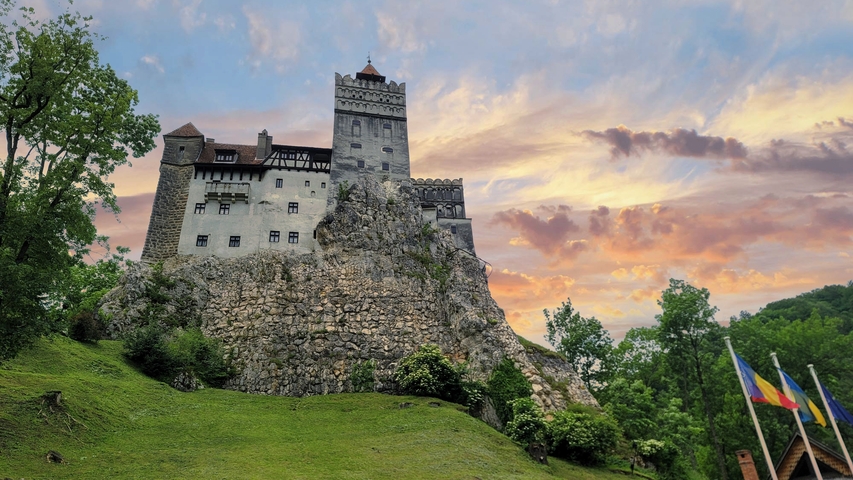 A famous castle on a hill during sunset with flags in the foreground.