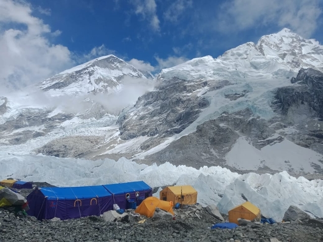       Tents set up at the base of a snowy mountain range.
  