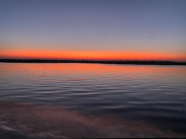       Silhouette of a sunset over a rippling river.
  