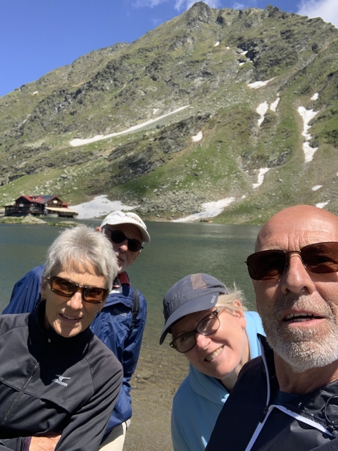 Group of people posing in front of a lake with mountain backdrop.