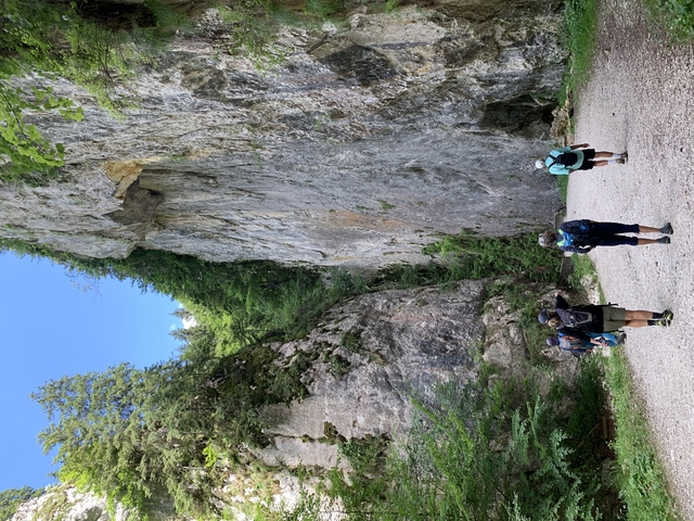       Group of hikers walking along a path with rocky walls.
  