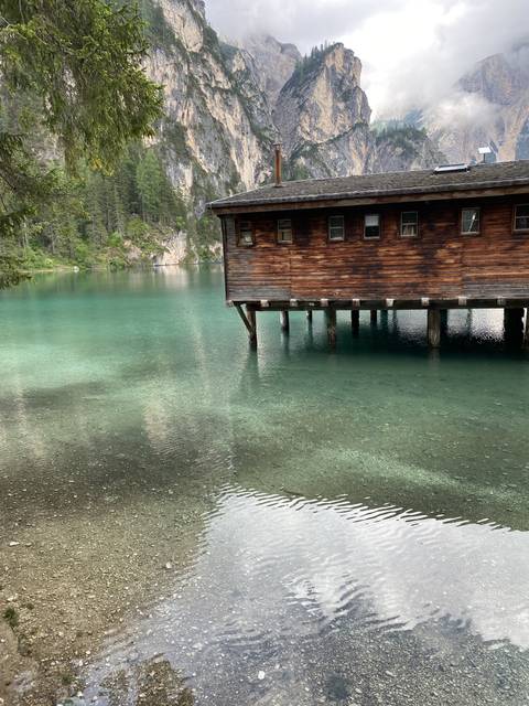 A wooden cabin on stilts over clear water.