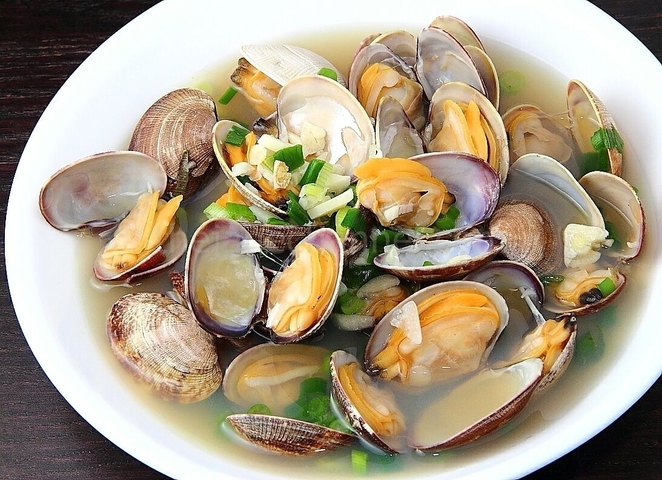 Plate of clams served with herbs and sauce.