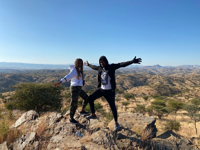 Two people posing on a rocky hill with a vast view.