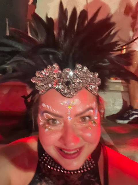 Person in carnival attire with a jeweled headdress and makeup.