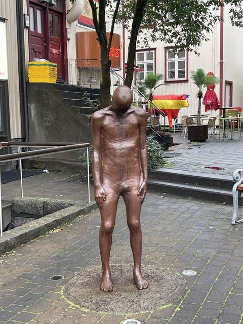       Rotated bronze statue on a street.
  