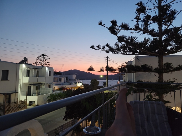       View of sunset from a balcony with modern buildings.
  