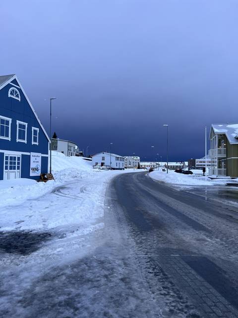 Snowy town street with blue skies above.