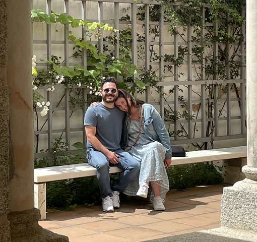 Couple sitting on a bench in a garden courtyard.