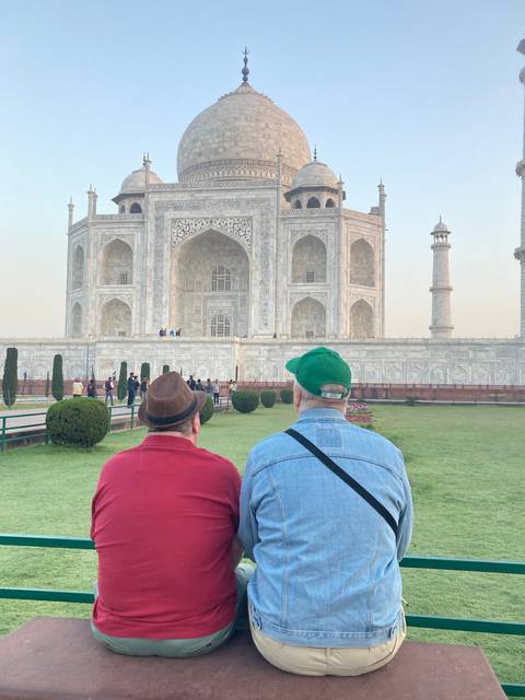 Two people sitting in front of a grand white monument.