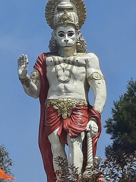       Statue of a deity with raised hand and ornate clothing.
  