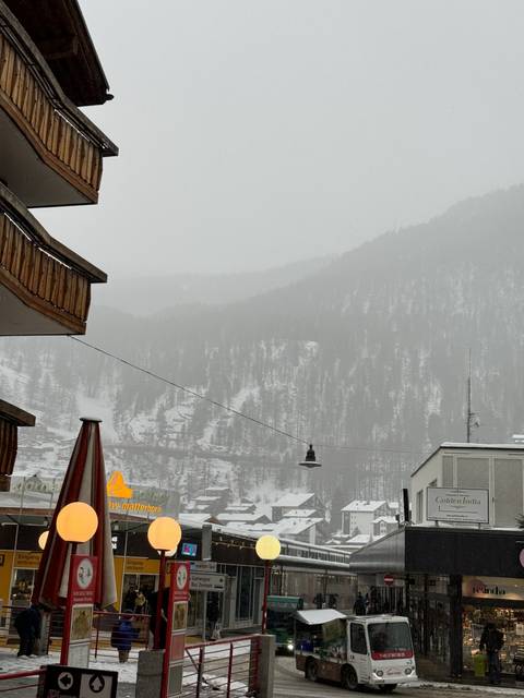       Snow-covered village during winter with mountains in the background.
  