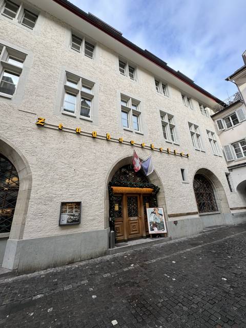       Building facade with Swiss flag above door.
  