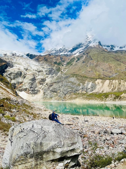       Person hiking by a turquoise lake with mountains in the background.
  