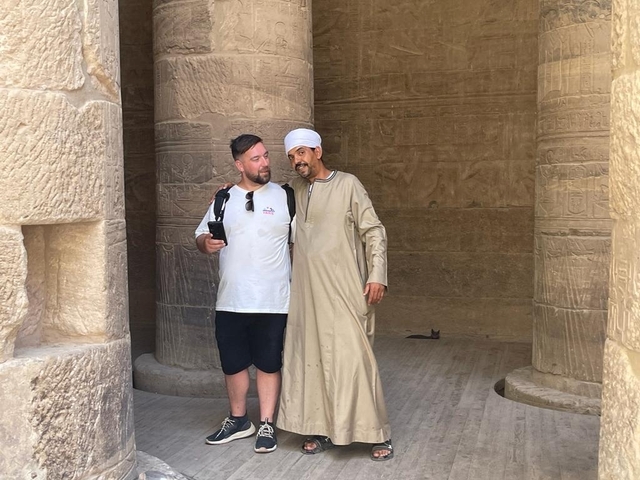 Two people standing in an ancient structure with hieroglyphics.
