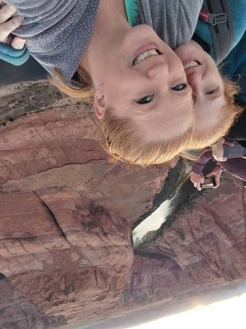       Two people taking a selfie over a winding canyon view.
  