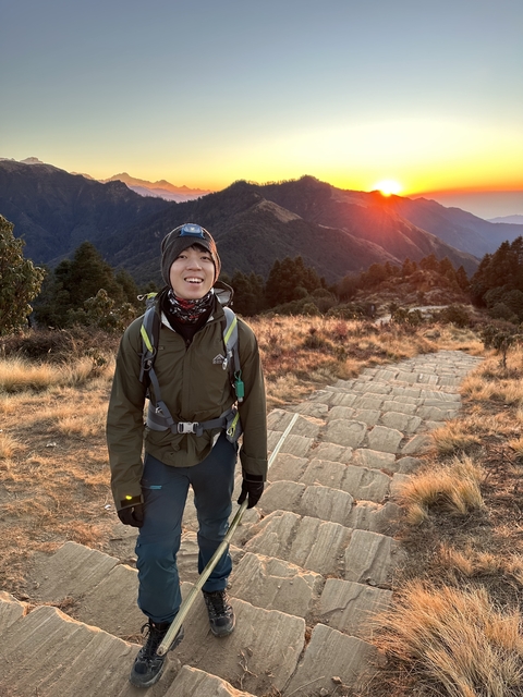 Person hiking on a mountain trail during sunrise.