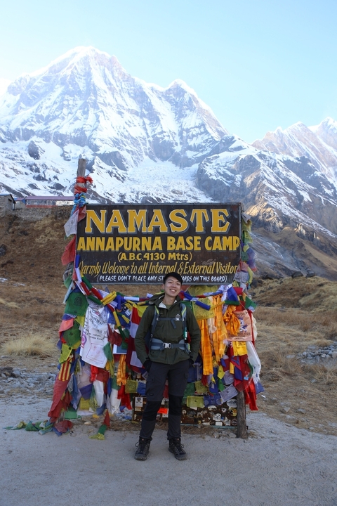 Person posing at Annapurna Base Camp sign.