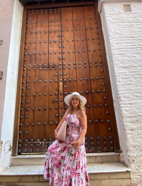 Person stands in front of a large wooden door with metal decor.