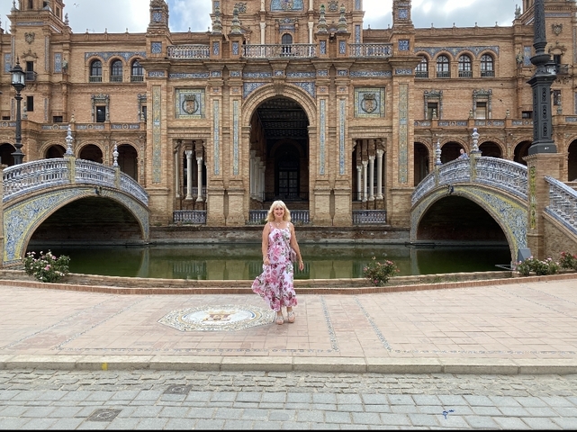       Person standing in front of the Plaza de España with arches and canal.
  