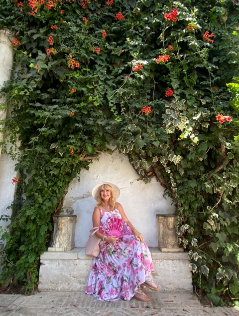       Person in front of a vine-covered wall with flowers on either side.
  