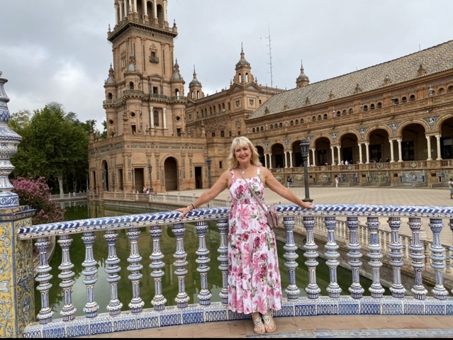      Woman standing at a railing in the Plaza de España with ornate tiles.
  