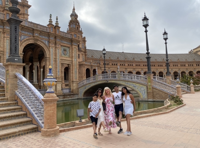       Group of people near a historic building with arches and a canal.
  