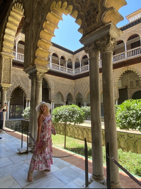       Person standing among ornate archways and columns of a historical court.
  