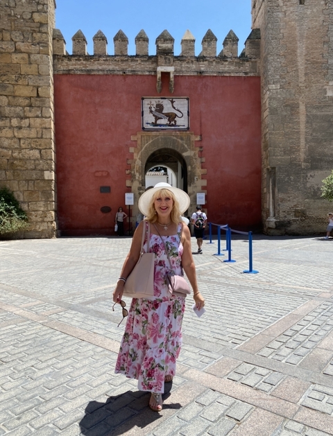       Person stands at a red building entrance in a bright courtyard.
  