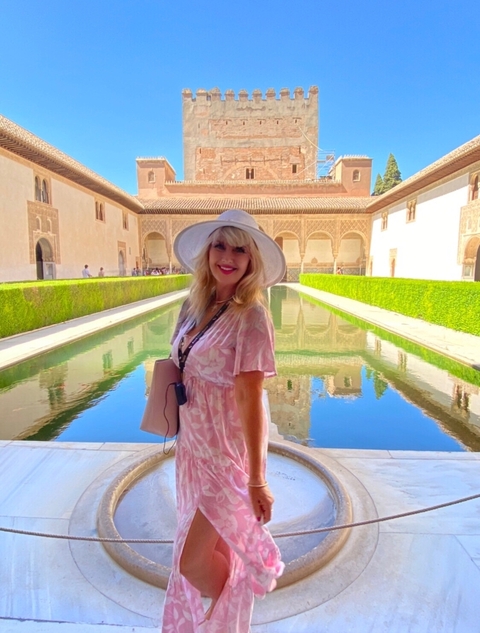 Person in front of a reflecting pool in a historical courtyard.