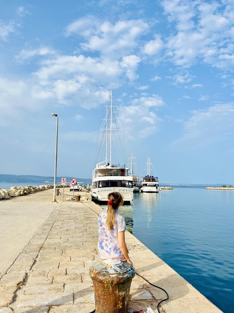       Woman walking towards docked boats.
  