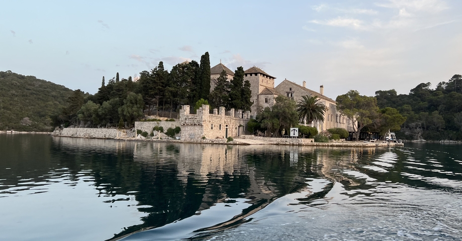       An abbey with surrounding water and reflection.
  