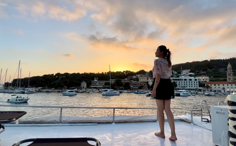       Woman enjoying a sunset view over a harbor.
  