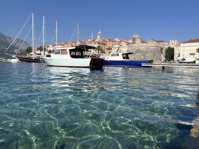       Clear water with boats docked and historic buildings in the background.
  