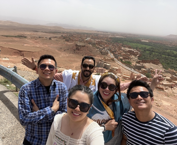       Group selfie with desert and town in the background.
  